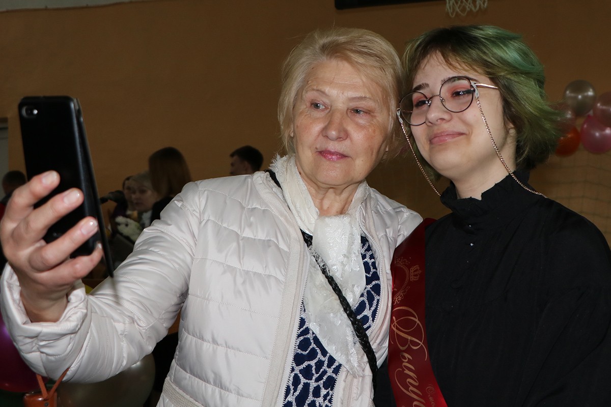 С выпускницей фотографируется бабушка.